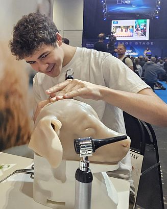 Smiling young man examines a latex dog head 