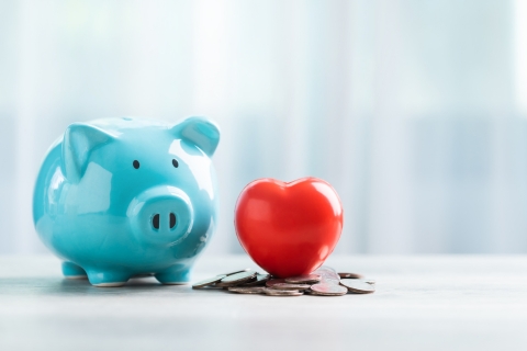 An image of a blue piggy bank with a read heart and and coins underneath