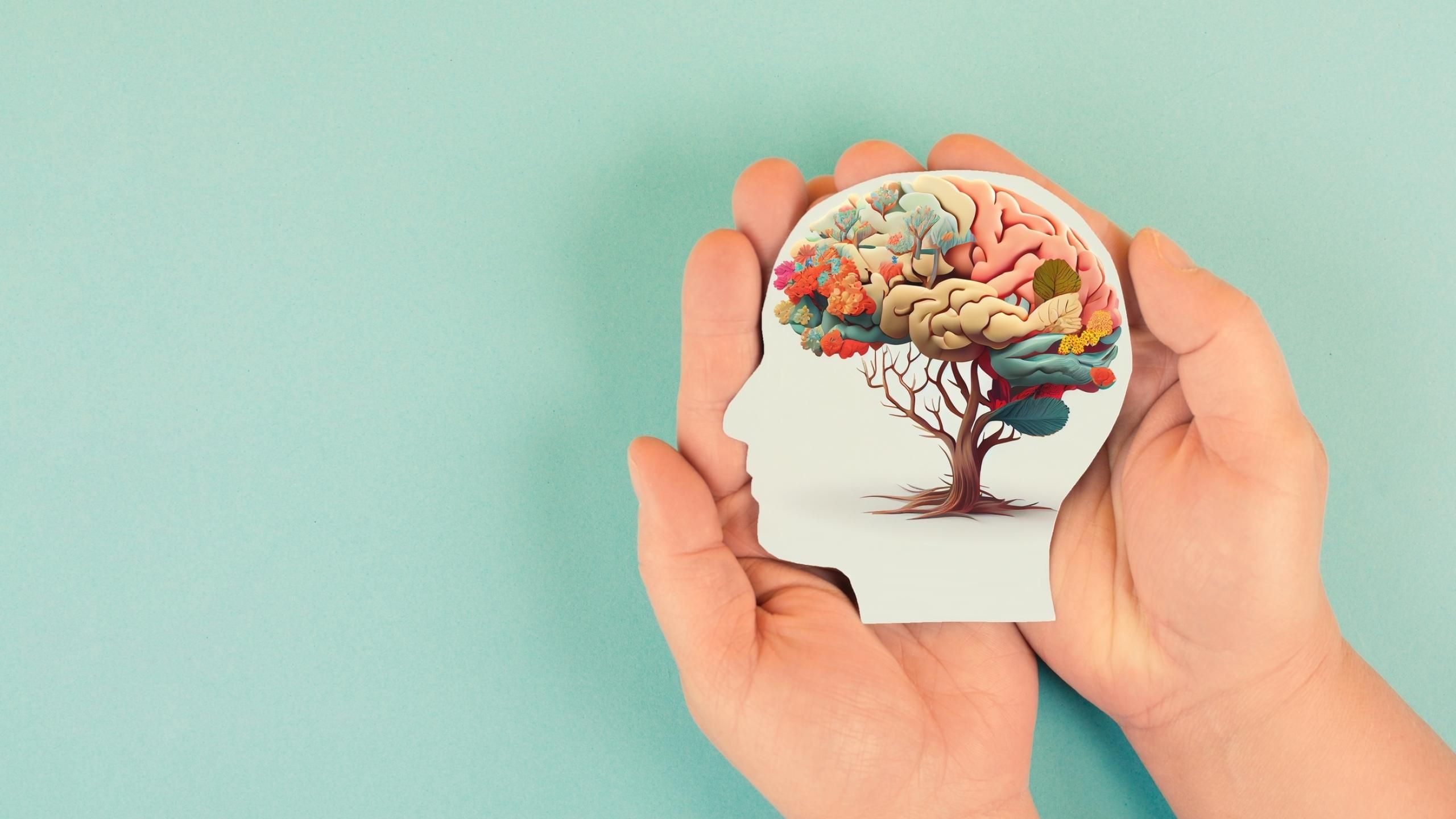 Two hands holding a picture of a face with a brain