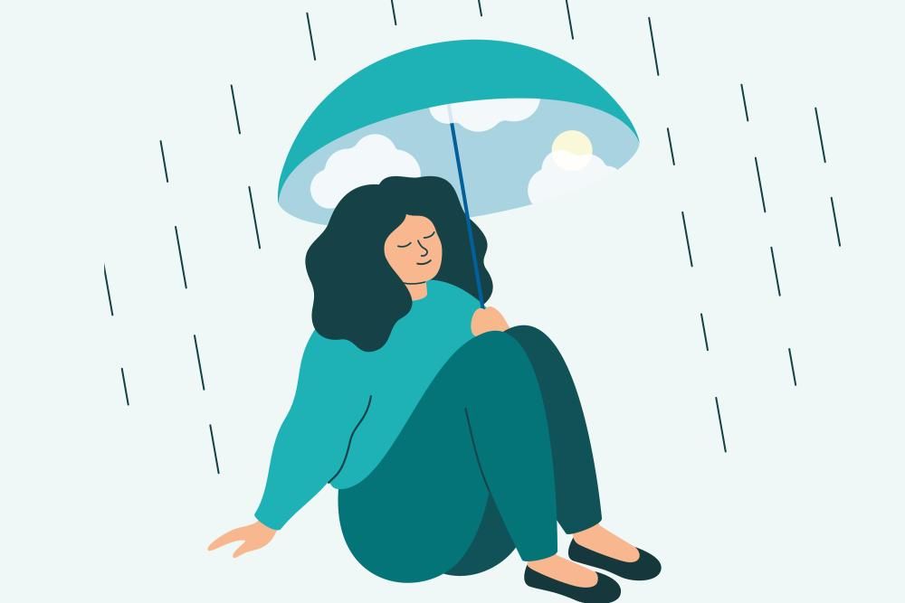A person sitting with an umbrella protecting them from the rain