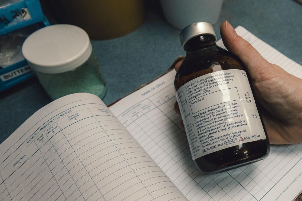 A hand holding a bottle of animal prescription medication