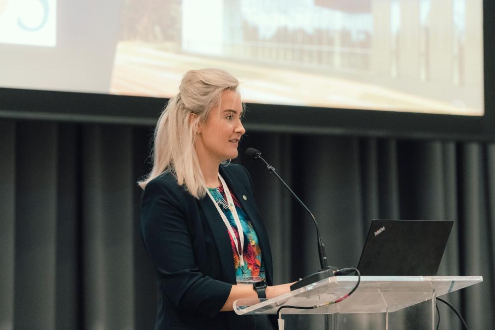 A person speaking at a lectern with a microphone 