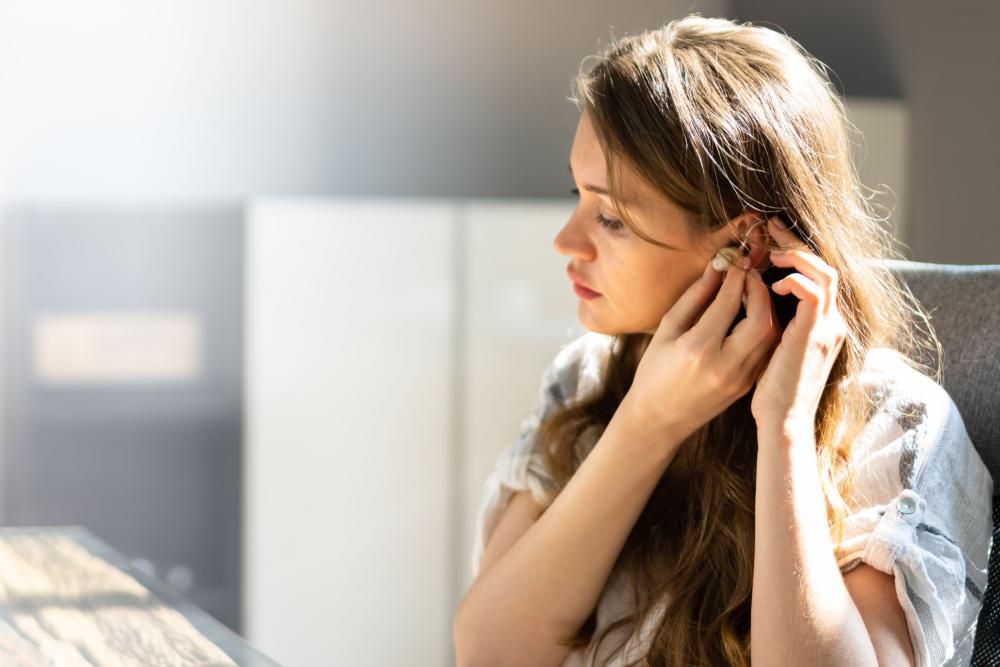 A woman adjusting her earpiece while sitting at a desk in an office