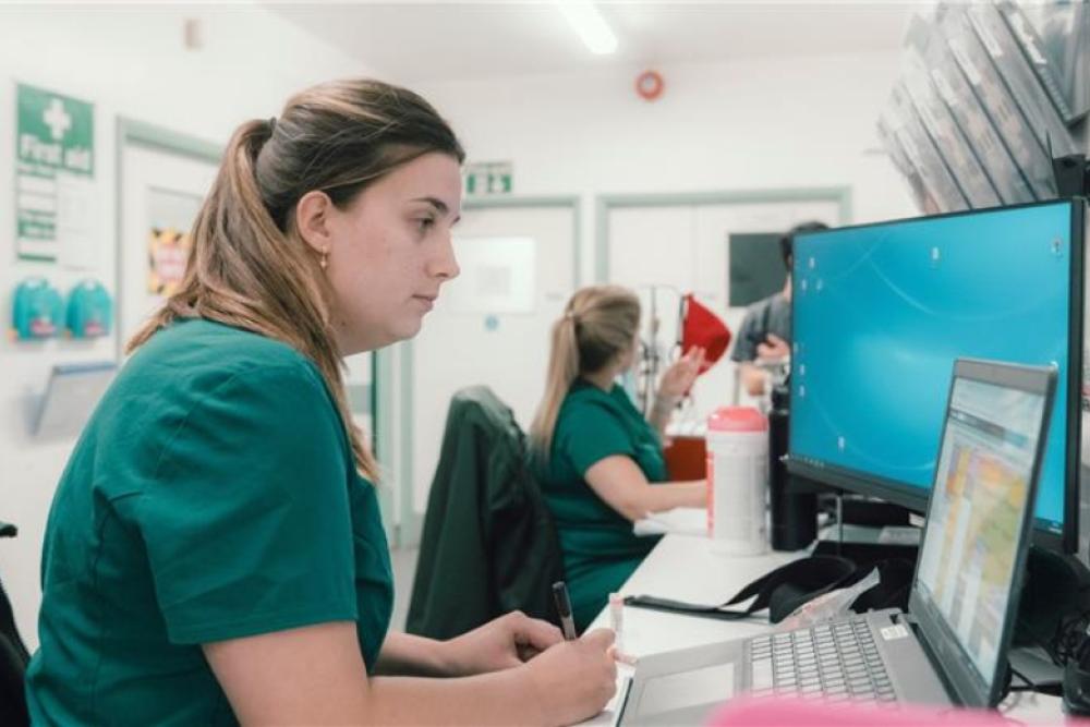 Veterinary professional sat in green uniform at her desk, working on the computer